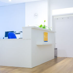 Heller Empfangsbereich in einer modernen Arztpraxis mit Schreibtisch und Bürostuhl.