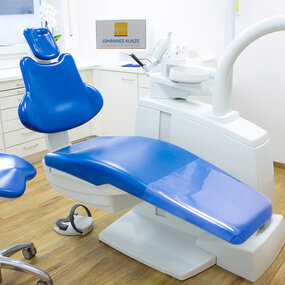 Moderner, heller Behandlungsraum in einer Zahnarztpraxis mit blauen Behandlungssesseln.