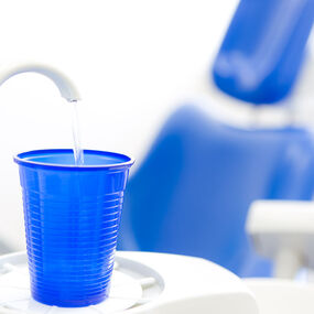 Blauer Plastikbecher wird an einem Zahnarztstuhl mit Wasser gefüllt, Zahnarztpraxis.